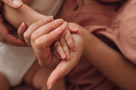 Close-up of mom's hand holding a small hand of a newborn baby. Maternity, preparation and motherhood , giving birth concept.の写真素材