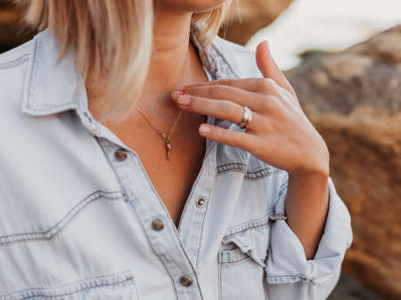Decoration on the girl's neck. The girl touches the chain around her neck with her hand. Close-up.