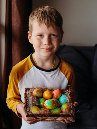 Easter holiday. A caucasian boy holding a basket of coloring Easter eggs. Vertical orientation.の写真素材