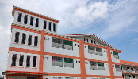 The dormitory building, looks high with many floors, behind the sky and clouds.