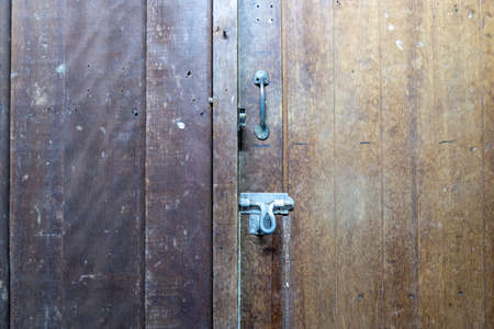 Old door bolts and handles, fixed with nuts, on wooden planks.