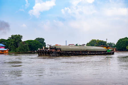 A cargo ship is sailing in the river, full of cargo.のeditorial素材