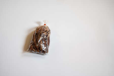 Dried bananas stored in plastic bags, with rubber bands, on a white background.