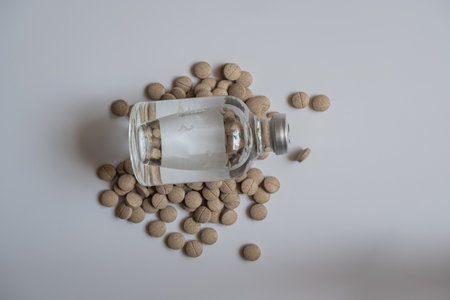 A big bottle of injection and a pill, placed together, on a white background.の写真素材