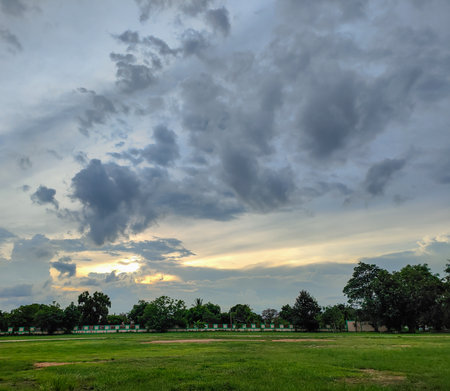The green field behind is a fence and trees. Above is the sky and clouds.の写真素材