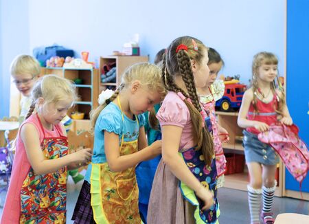 Girls tie aprons each other in kindergarten. Syktyvkar, Russia, September 8, 2011のeditorial素材