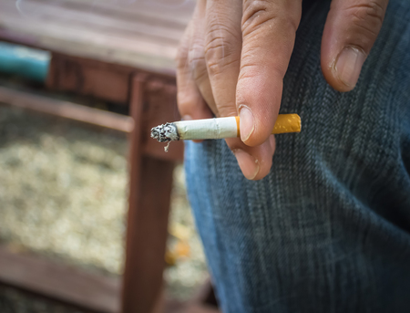 man hand holding a cigarette with smokeの写真素材