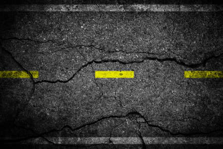 Cracks on asphalt the yellow line dividing lanesの写真素材