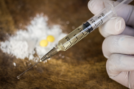 Syringe and heroin on wooden background with shadow edge. Drug addictionの写真素材