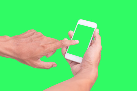 Hand shows mobile smartphone with green screen in vertical position isolated on green background
