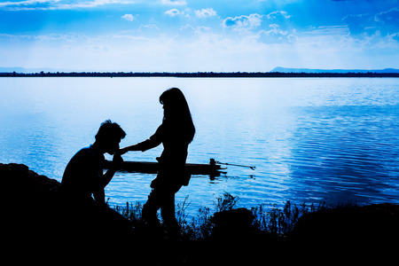 Silhouettes of man and woman kissing hand while at night