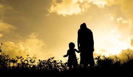 silhouettes of a women with her kid during sunsetの写真素材