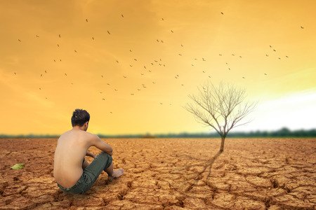 man sit on cracked earth near dry land and hot dry air.