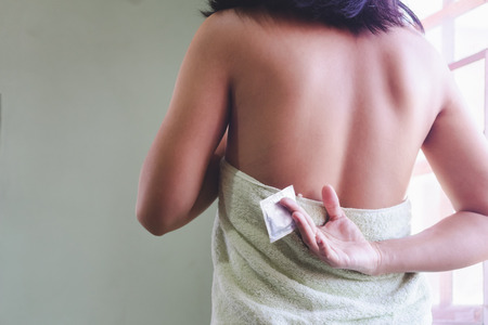 Adult sexy woman prepare a condom for use in safe sex to protect from disease aidsの写真素材