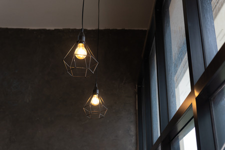 light bulb in black steel cage hang on ceiling in coffee shop, Fashion and lamp in modern style.