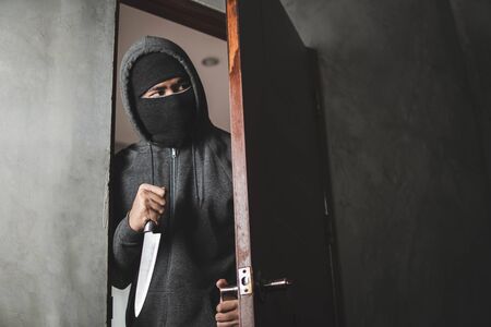 The thief holds a knife to open the house door for robbery.の写真素材