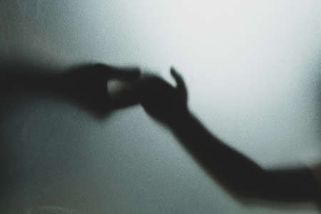 Ghost concept shadow of hand behind the matte glass blurry hand and body soft focusの写真素材