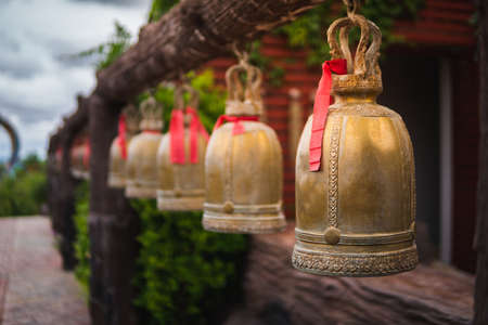 Old Thai golden bells hang on a wooden pole beside the corridor.の写真素材