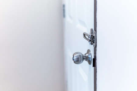 Stainless steel door knob on a closed white painted doorの写真素材