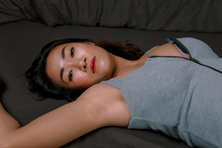 Sexy Asian woman in gray dress on black bedの写真素材