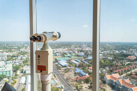Binocular on top of the building on rooftop viewing tower over building city