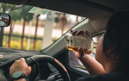 Man drinking alcohol while driving in his carの写真素材