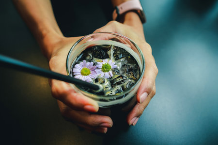 Black coffee in a glass on the hand of a girl in cafeの写真素材