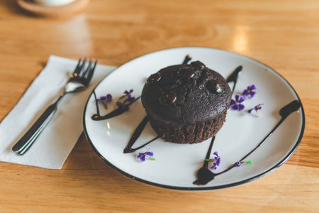 Chocolate cake circle decorated with flowers on a plate in a cafeの写真素材