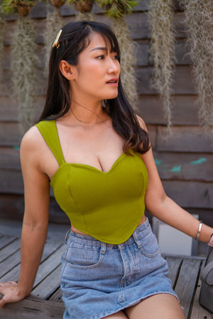 Portrait of beautiful sexy asian woman Wearing a green strapless dress and jean skirt in a cafeの写真素材