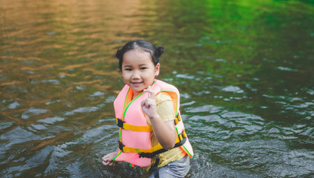 little girl playing in water By wearing a life jacket for safetyの写真素材