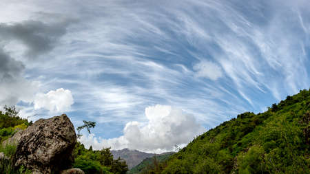 Beautiful clouds against the background of mountains and green trees. Mountain landscape of the...