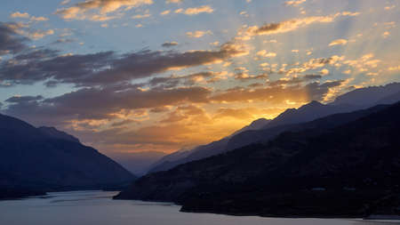 Dawn in a mountain lake. The sun shines through the clouds. Mountain landscape at sunriseの写真素材