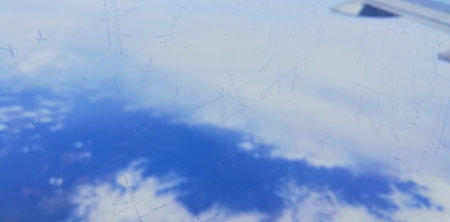 Airplane window with snow and blue sky as background. Close up.