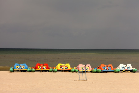 Colorful water bicycles waiting on the Black Sea beach in a storm dayの写真素材
