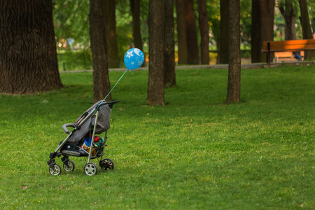 Baby trolley isolated in a park with blue baloonの写真素材