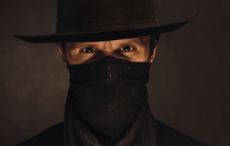 Portrait of young handsome man cowboy in a black hat and scarf