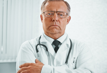 Portrait of serious older man doctor in hospitalの写真素材