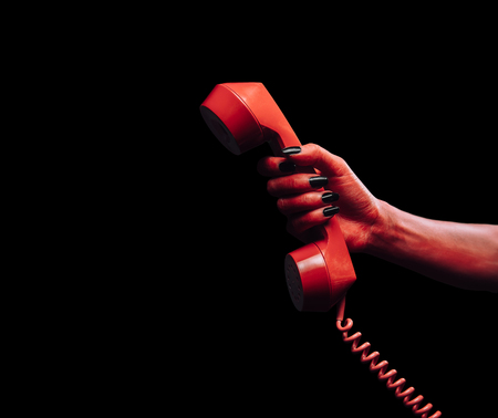 Red demon hand gives phone handset on dark , space for text, Halloween or horror themeの写真素材