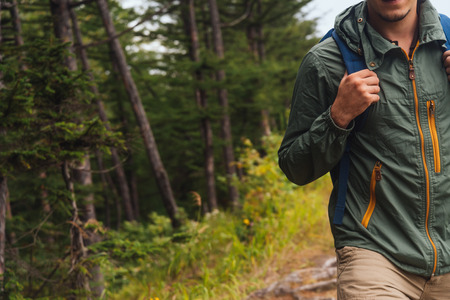 Smiling young hiker man with backpack walking in summer forest, copy-space in left part of imageの写真素材