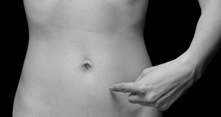 Woman points to a thin abdomen, space for text, face is not visible, monochrome imageの写真素材