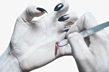 Unrecognizable dead woman writing on her hand by scalpel. Space for text on hand, Halloween/horror themeの写真素材