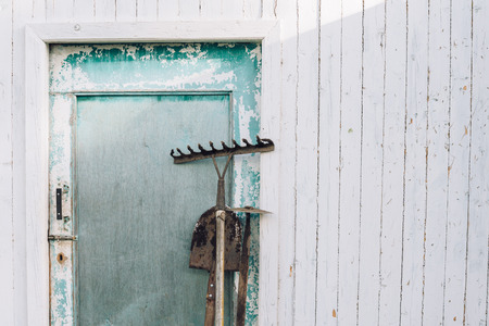 Gardening equipment: hoe, shovel and rake near a shed