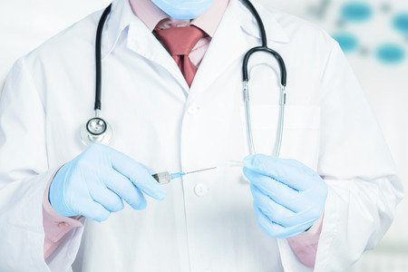 Male doctor in gloves puts a cap on the syringe in hospitalの写真素材