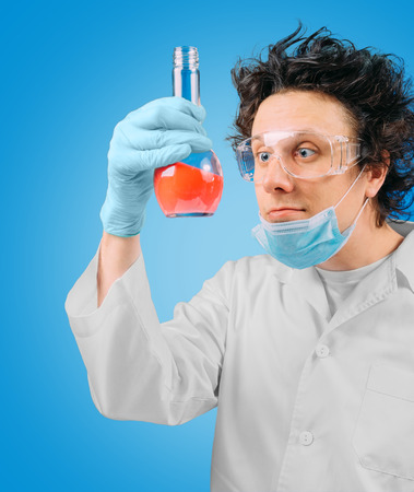 Crazy laboratory technician is looking at test tube with red liquidの写真素材