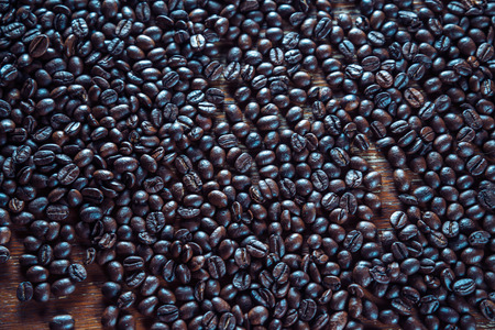 Roasted coffee beans are scattered on a wooden background, textureの写真素材
