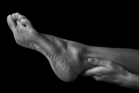 Woman holds her leg, pain in the leg, monochrome imageの写真素材