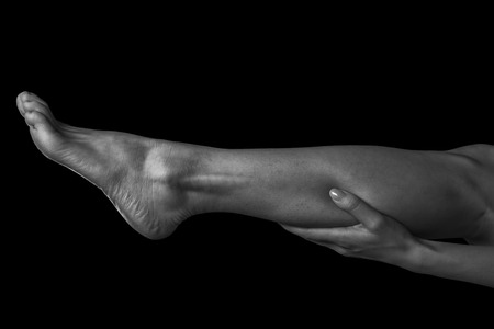Woman holds her leg, pain in the female calf muscle, monochrome imageの写真素材