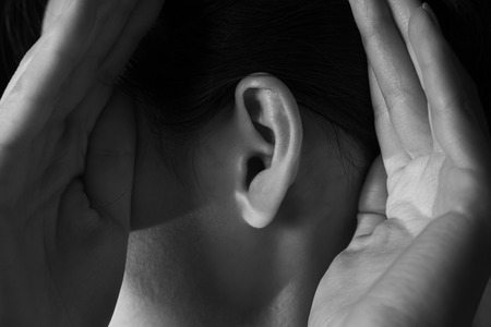 Unrecognizable woman holds her hands near ear and listens, monochrome imageの写真素材