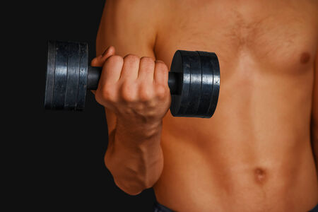Muscular shirtless man is lifting dumbbell, face is not visibleの写真素材