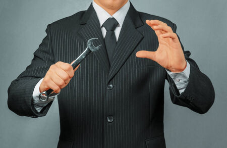 Unrecognizable businessman holds metal wrench, focus on wrench, concept of business creationの写真素材